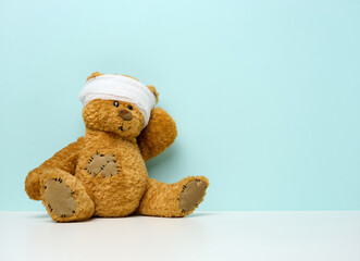 children's toy teddy bear sits with a bandaged head. childhood trauma concept
