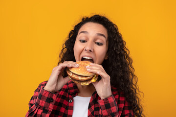 Wall Mural - Funny Latin Lady Holding Burger Biting Sandwich At Studio