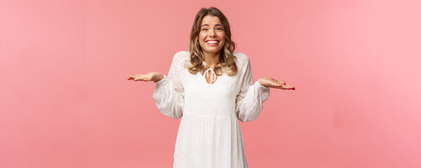 Wall Mural - Beauty, fashion and women concept. Sorry dont know, cant say. Cheerful cute silly blond girl 20s, wear white dress, shrugging with hands sideways make awkward smile, apologizing, pink background