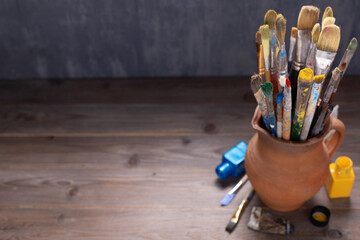 Poster - Paint brush in clay jug and tools on wooden table background texture. Paintbrush for painting