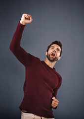 Aufkleber - Now thats worth celebrating. Studio shot of a handsome young man cheering against a gray background.