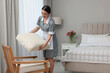 Young chambermaid cleaning up bedroom in hotel