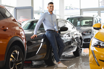 Wall Mural - Confident arab guy businessman buying new car at dealership salon