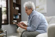 Elderly woman with poor posture using tablet in living room