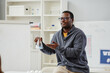 © Seventyfour - Portrait of African American science teacher explaining chemistry in school class and holding glass beaker with colored liquid, copy space