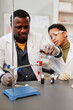 © Seventyfour - Vertical portrait of African American teacher demonstrating science experiments in school chemistry lab