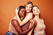 © iordani - young pretty asian, caucasian, african woman posing cheerful together on brown background, lifestyle diverse nationality people concept