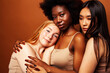 © iordani - young pretty caucasian, african, scandinavian woman posing cheerful together on brown background, lifestyle diverse nationality people concept