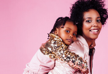 young pretty african-american mother with little cute daughter hugging, happy smiling on pink background, lifestyle modern people concept