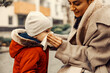 © Dusan Petkovic - A babysitter blowing the nose of a sick little boy at the park in cold weather.