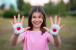 © Svetlana - Happy funny smiling child girl show open hand raised painted in Japan flag colors outdoor