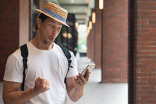 Happy Excited Man Traveler Using Smartphone, Discovering Grand Sale Offer, Good Online Deal, Fast Internet Connection