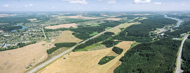 Wall Mural - aerial panoramic view of road among agricultural fields on a bright sunny day.