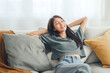 © oatawa - Closeup - Relaxed young asian woman enjoying rest on comfortable sofa at home, calm attractive girl relaxing and breathing fresh air in home, copy space.