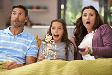 Poster - They love scary movies. Shot of a family sitting on their living room sofa watching a movie and eating popcorn.