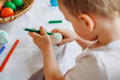 © Antonina Trushina - a boy paints Easter eggs, draws cars with a felt-tip pen