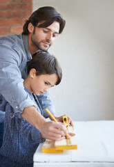 Learning everything dad has to teach. A father and son doing woodwork together.