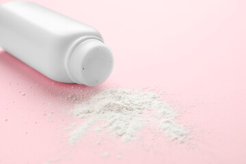 Bottle and scattered dusting powder on pink background, closeup. Baby cosmetic product