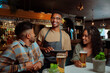 © Prins Productions - African American male waiter serving couple and friends at the restaurant
