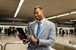 © Westend61 - Happy businessman using tablet PC at train station