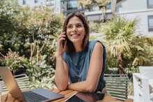 Smiling Businesswoman Talking On Smart Phone At Back Yard