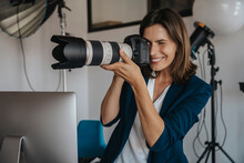 Smiling Photographer Photographing Through Digital Camera In Studio