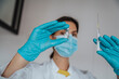 © Westend61 - Female doctor with surgical glove holding syringe and vial in clinic