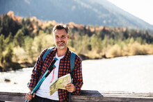 Austria, Alps, Smiling Man On A Hiking Trip With Map On A Bridge
