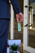 Businessman Holding Key With Label Standing In Office