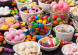 Variety of milk chocolate and jelly sugar gum sweets and candies on black background. Best snacks for kids parties.