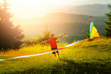 Little Boy At Sunset Launches Large Kite With Long Huge Forked Tail. Sunny Summer Or Spring Day. Summer Vacation And Healthy Lifestyle Concept.