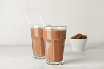 Wall Mural - Glasses of delicious chocolate milk on white wooden background