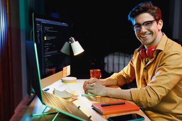 Side profile view happy young geek software database engineer IT specialist programmer man in shirt work at home office writing code on laptop pc computer typing script. Program development concept.