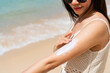Young Asian woman apply sun protection on to her hand. Summer on beach concept.