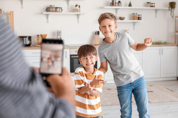 Wall Mural - Man taking photo of his dancing sons in kitchen