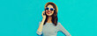 Portrait of happy smiling young woman calling on smartphone on blue background