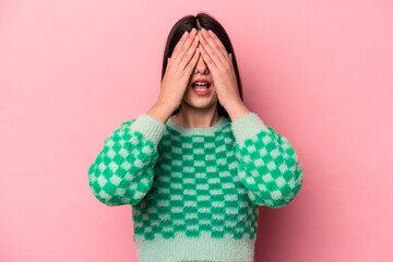 Wall Mural - Young caucasian woman isolated on pink background having fun covering half of face with palm.