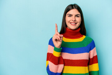 Young caucasian woman isolated on blue background showing number one with finger.