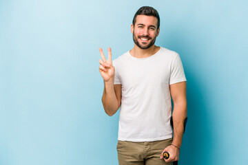 Wall Mural - Young man with crutches isolated on blue background showing number two with fingers.