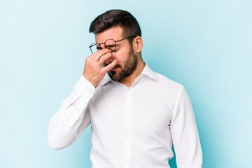 Young caucasian man isolated on blue background having a head ache, touching front of the face.