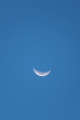 View of a beautiful waning crescent moon in a blue sky