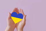 Fototapeta Tęcza - love blue and yellow heart in hands on colorful background.  Ukraine concept 