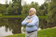 © Studio Romantic - Happy retirement and pension. Aged male retired person walking in urban city park on weekend. Smiling dreamy senior man looking forward standing near lake pond having pleasant thoughts
