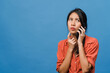 © tirachard - Young Asia lady talk by phone with negative expression, excited screaming, cry emotional angry in casual cloth and stand isolated on blue background with blank copy space. Facial expression concept.