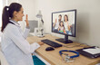 Online family doctor at desk with stethoscope smiling and waving hello at desktop computer screen greeting parents and child at telemedicine consultation via video call in modern convenient webcam app