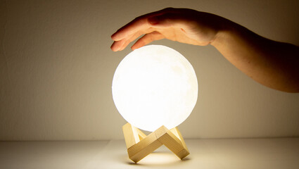 Wall Mural - moon lamp turn on with white background with a hand over it