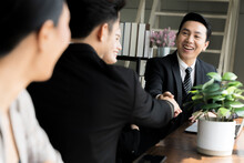 A Businessman In An Asian Suit Is Chatting Happily With His Colleague At The Company Window In A Casual Manner.