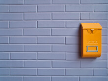 Cute Yellow Mailbox On A Purple Brick Wall