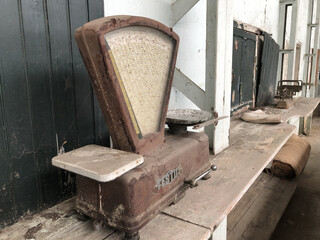 Sticker - An old rusty scale on a shelf against black and white wall in an ancient hats factory during daytime