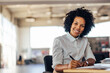 © bnenin - Portrait of a lovely African-American woman with curly hair, holding a pen.
